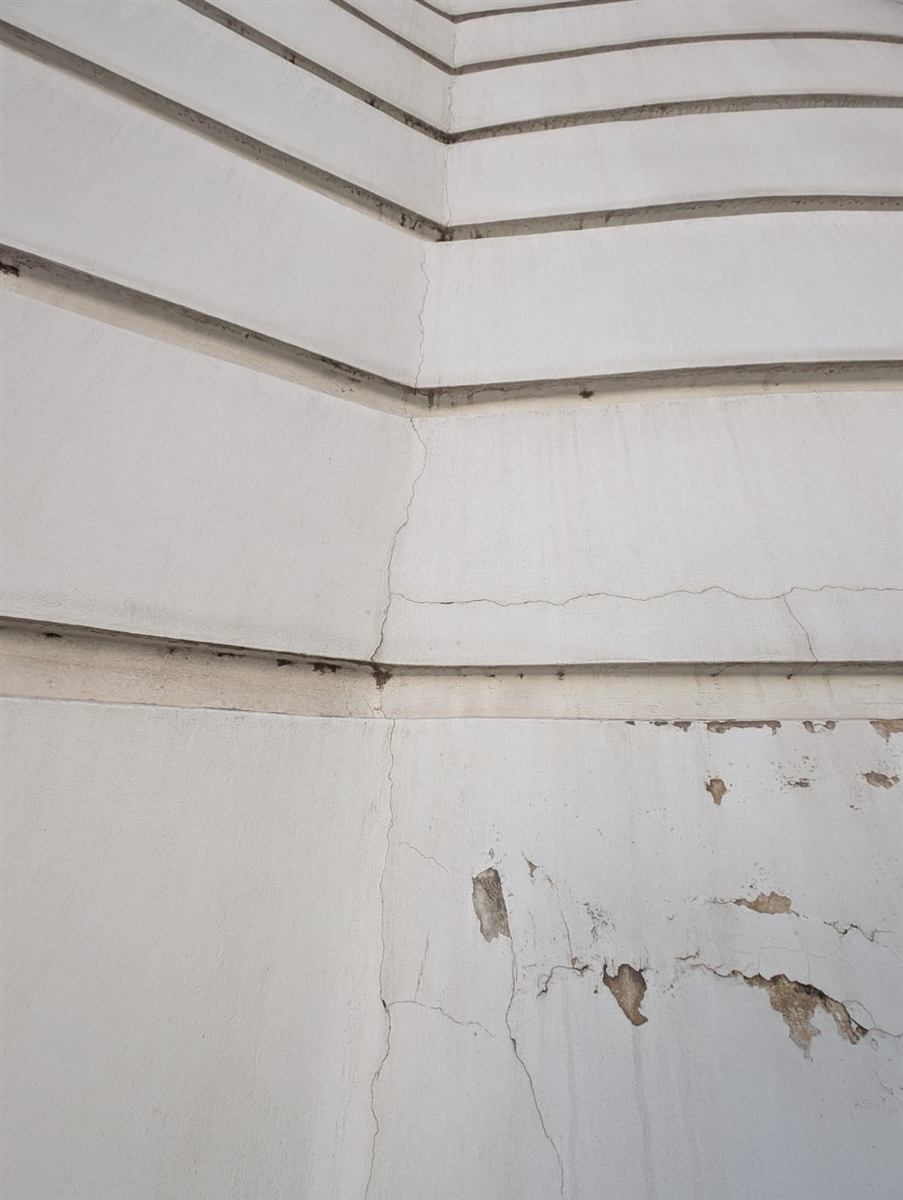 Fissures en angle de façade : fissure verticale dans l'angle rentrant, fissures horizontales et enduit décollé par plaques.